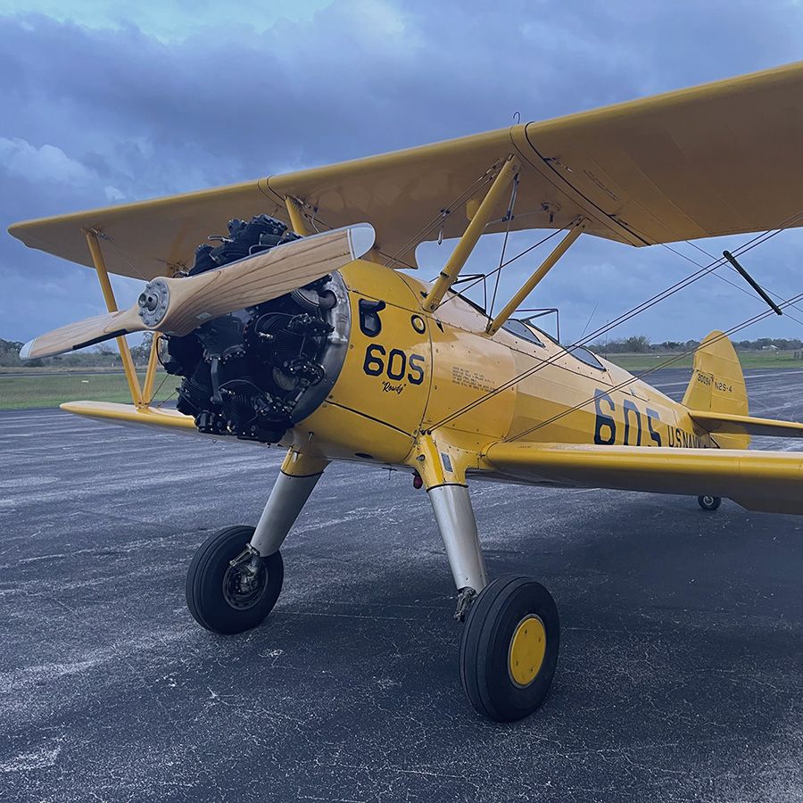 yellow stearman on the taxiway on an overcast day