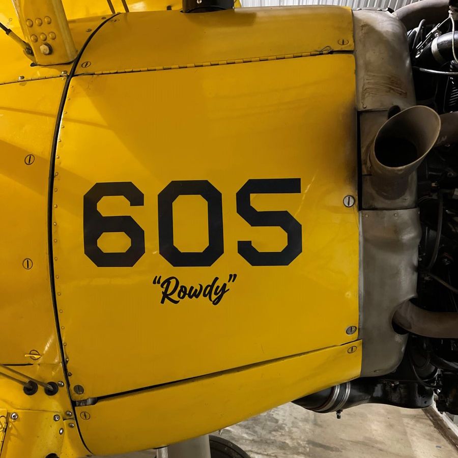 extreme close-up of airplane cowling with number 605 and “Rowdy” written in black on yellow