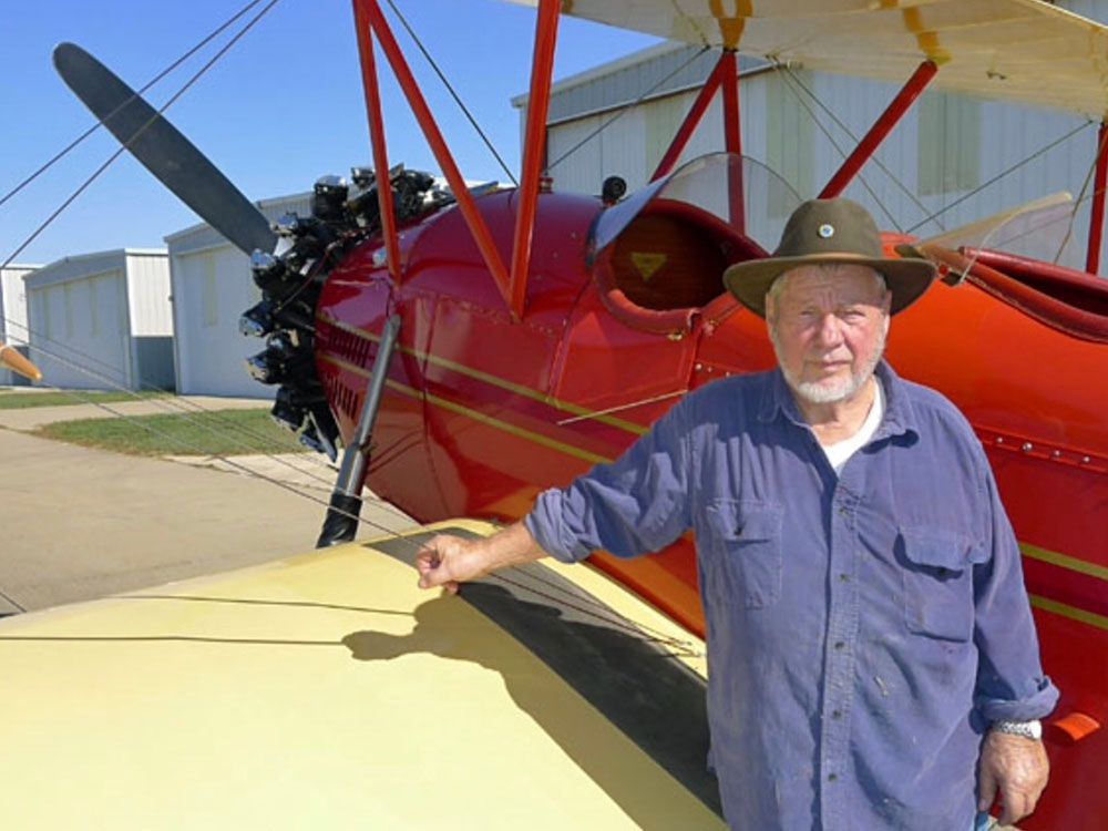 john cournoyer in front of red and yellow bi-plane