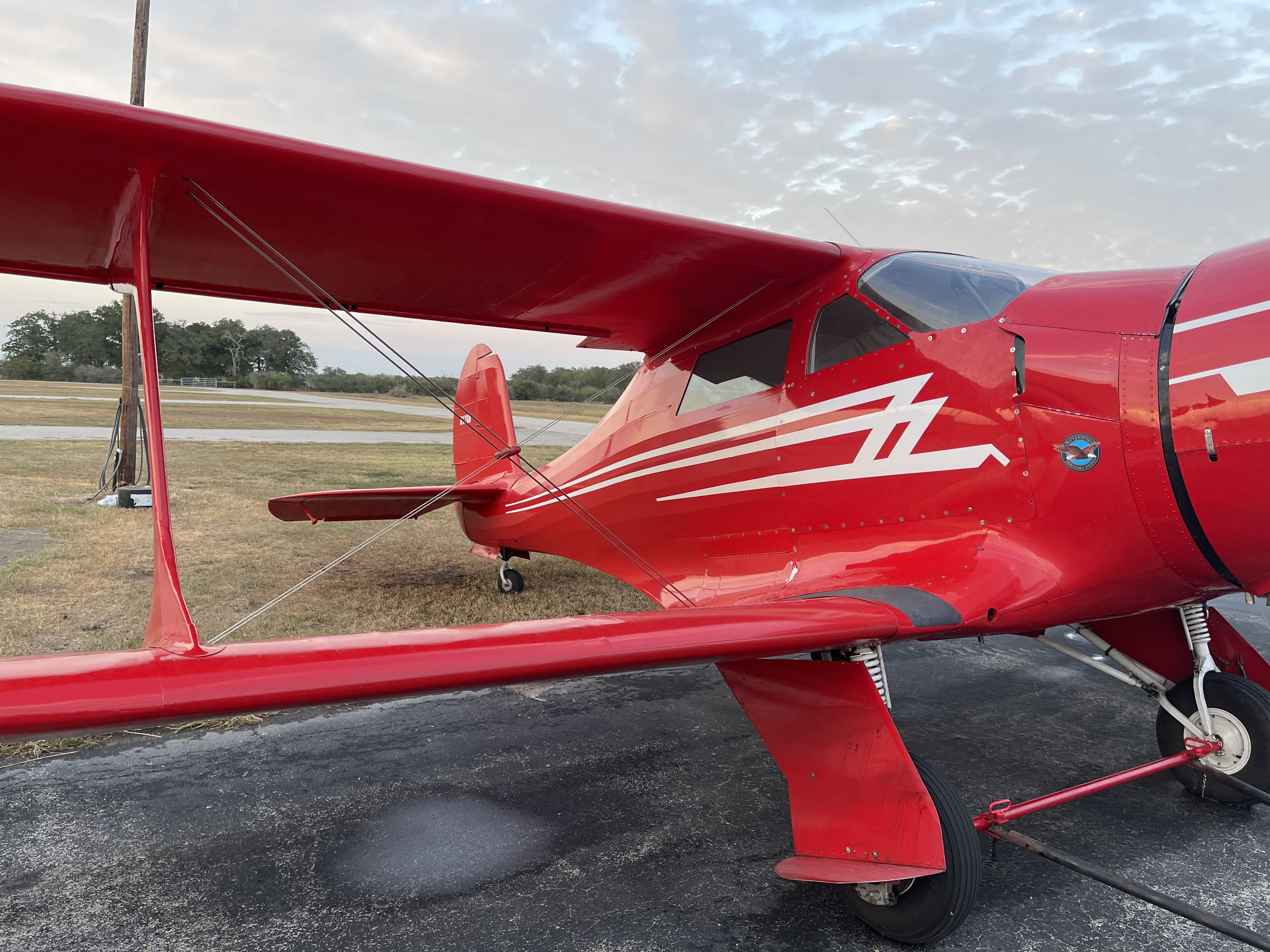 white with blue trim staggerwing in hangar, 3/4 front view