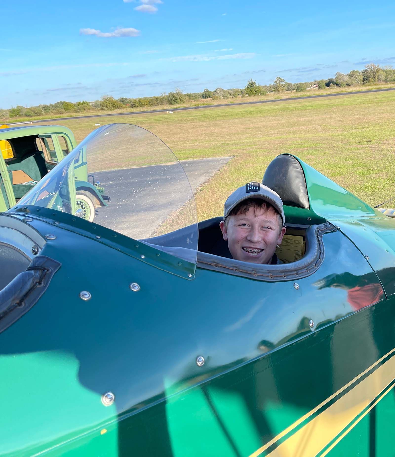 close up of smiling boy in the open cockpit of a 1929 fleet biplane