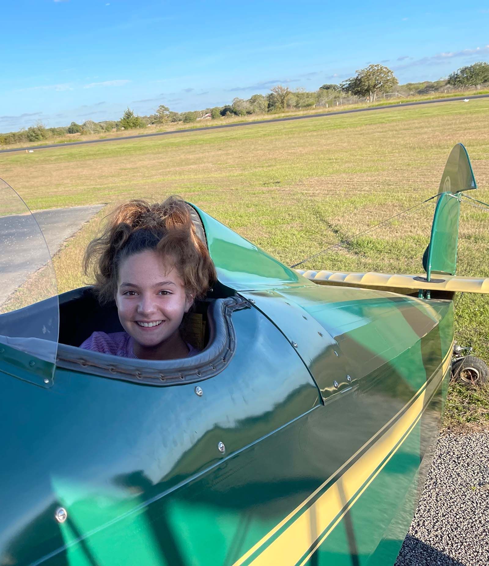 close up of smiling girl in the open cockpit of a 1929 fleet biplane