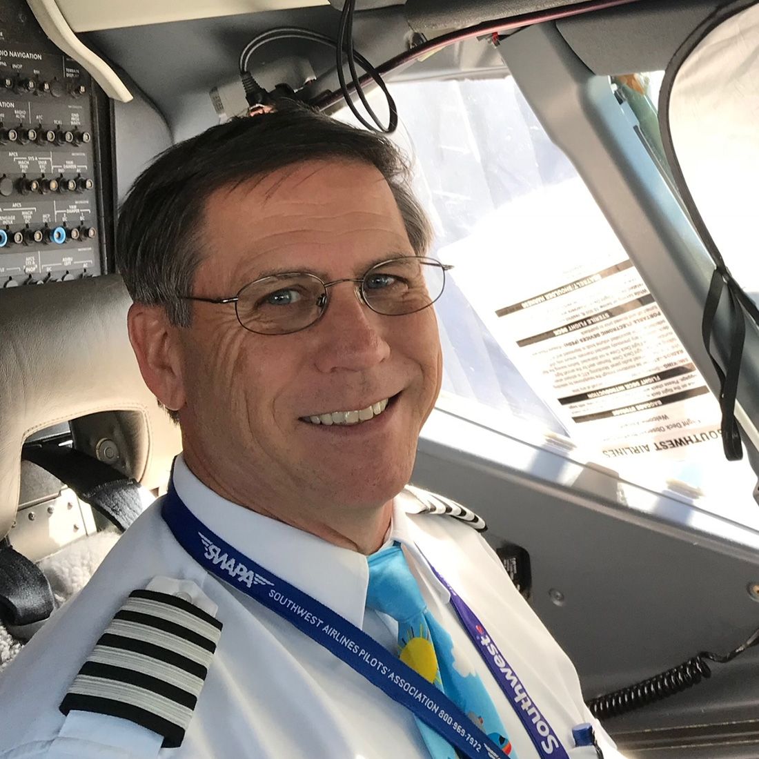 Paul Britton wearing a captain’s uniform in the cockpit of a commercial jet