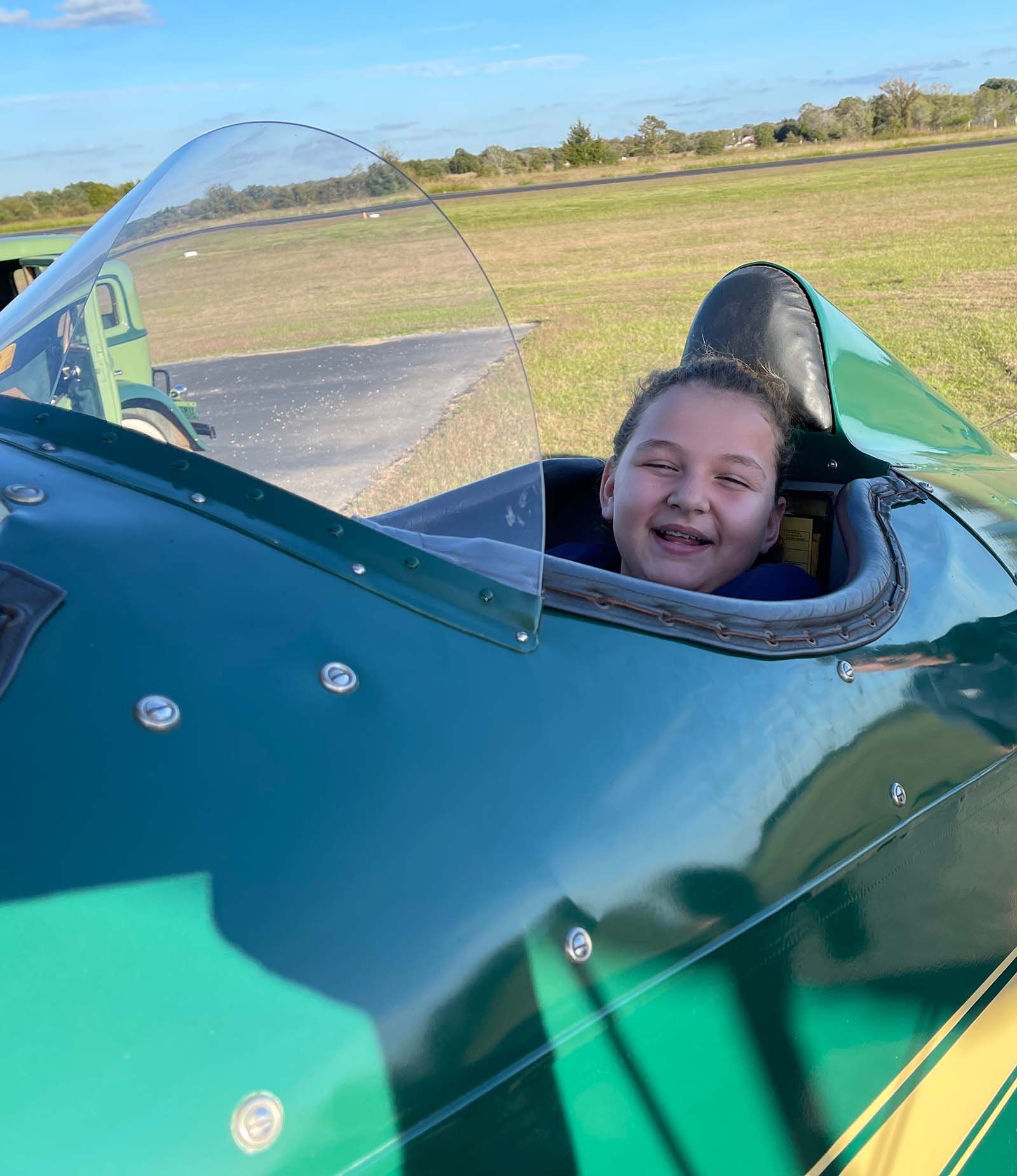 close up of smiling girl in the open cockpit of a 1929 fleet biplane